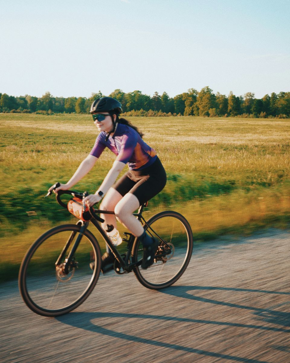 Ciclista de gravel pedaleando por una pista de tierra al atardecer